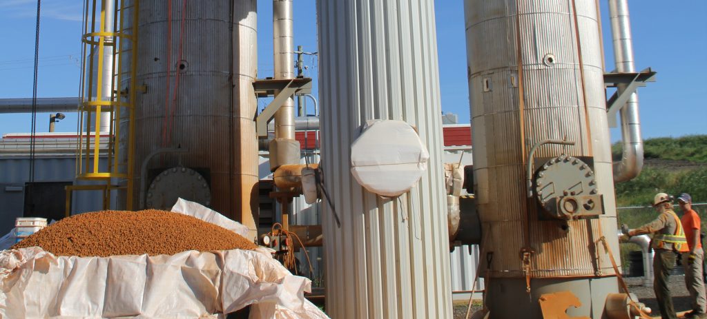 Industrial gas purification facility featuring tall metal columns and a pile of pelletized filter media, showcasing advanced hydrogen sulfide removal processes for sustainable energy production." These details emphasize the image's focus on advanced gas purification technologies and their role in sustainability
